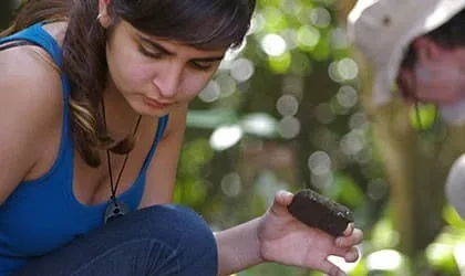 Intern examining an artifact in the field
