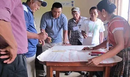 Community members discussing Maya land rights around a map