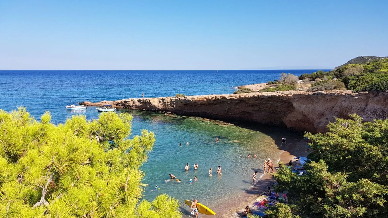 Swimmers in a clear blue cove on the coast near Athens