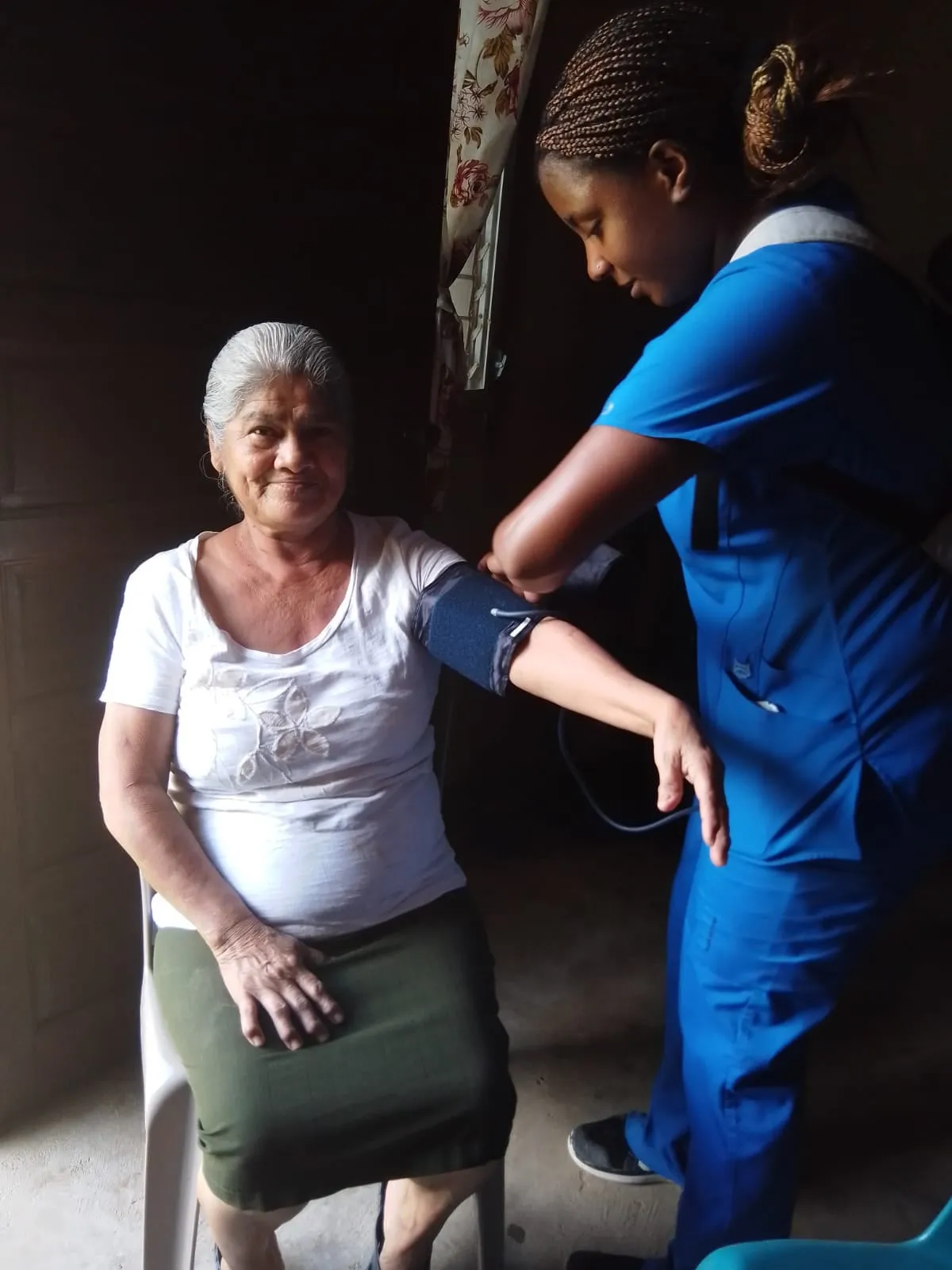 Nursing student checking an elder's blood pressure on a home visit in Belize