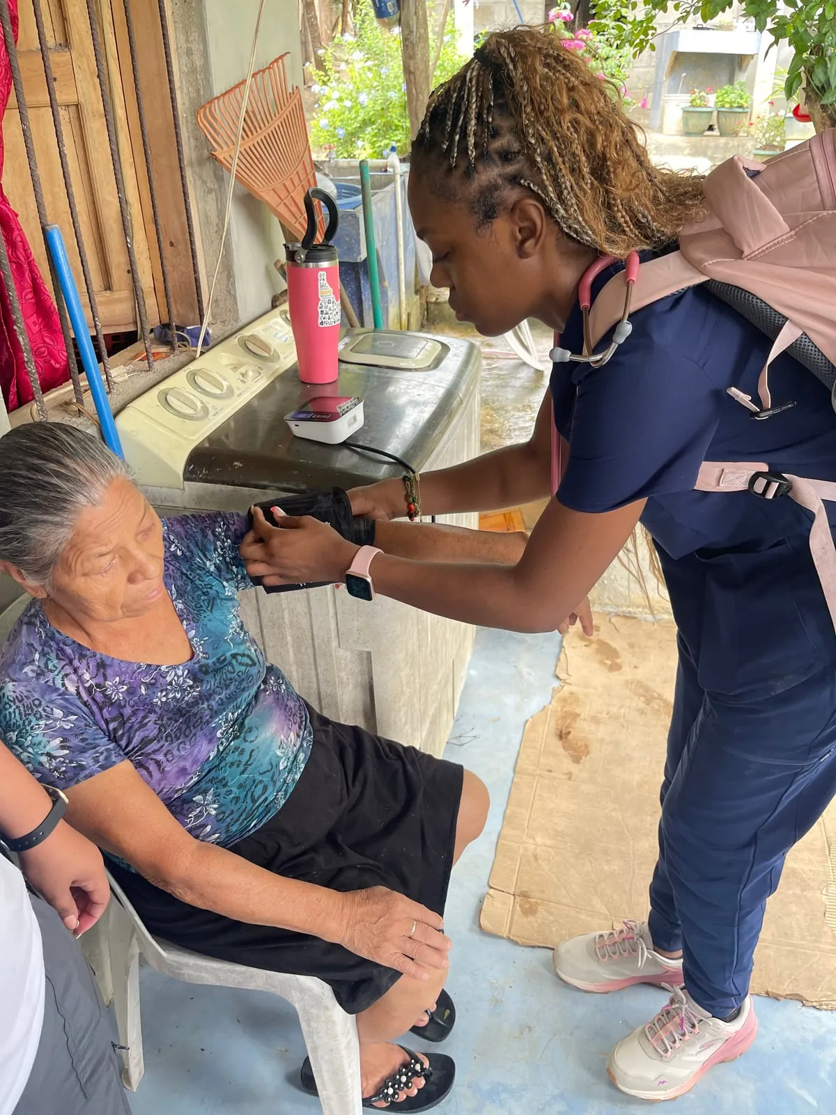 Nursing student checking a woman's blood pressure on a home visit in Belize