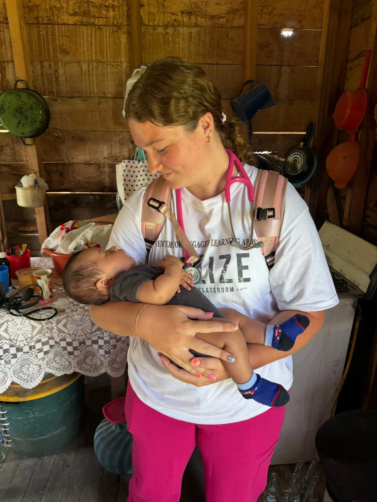 Nursing student holding a baby during a community visit in Belize