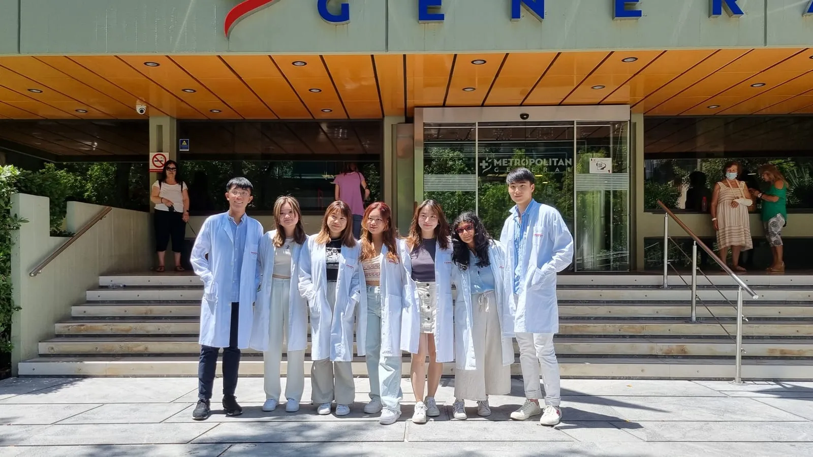 Students in white coats on the steps of Metropolitan General Hospital in Athens, Greece