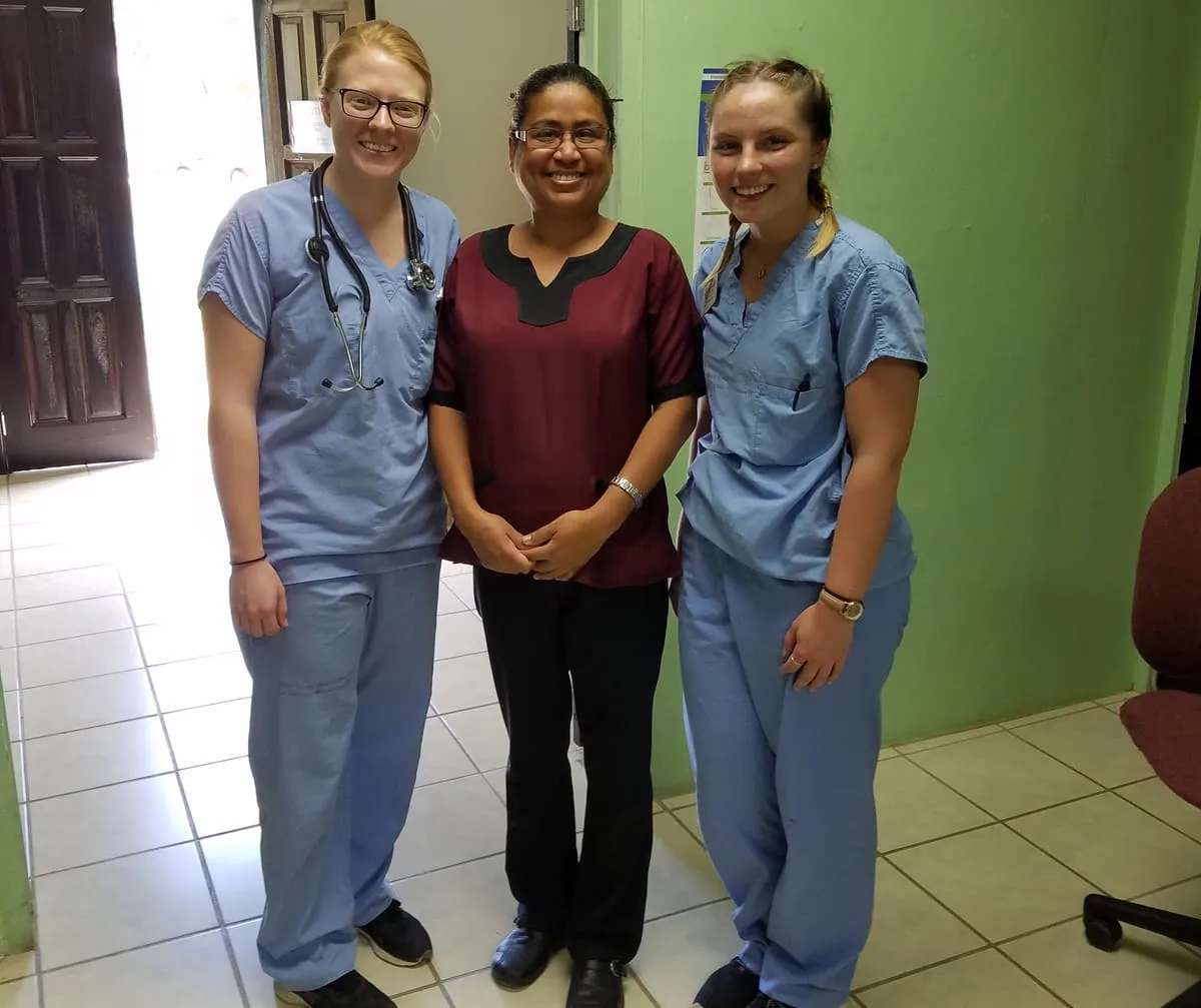 Three nursing students in scrubs at a clinic